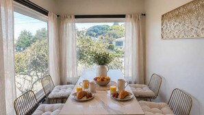 Un espace repas comprenant une table, des chaises et donnant sur l’extérieur.
