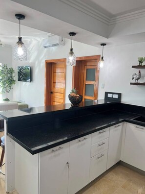 A kitchen with a black countertop, white cabinets, and pendant lights. - Beachfront Penthouse w/ Rooftop, Pools & Views (Punta Cana)