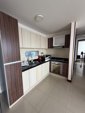 A modern kitchen with a built-in stove, microwave, and sink. - Apto Lili - Cali - Wifi - Familiar, Piscina (Cali)