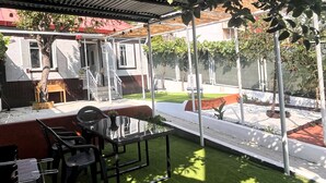 An outdoor patio with a glass table and chairs, a barbecue grill, and a covered seating area. - Quiet family house close to the historic centre, thermal baths and hospital (Ourense)