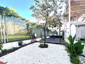 A garden area with a gravel path, a tree, and a hose reel.