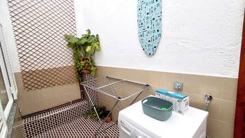 Un área de lavandería con lavadora, tendedero y un secador de pared.