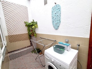 Un área de lavandería con lavadora, tendedero y un secador de pared.