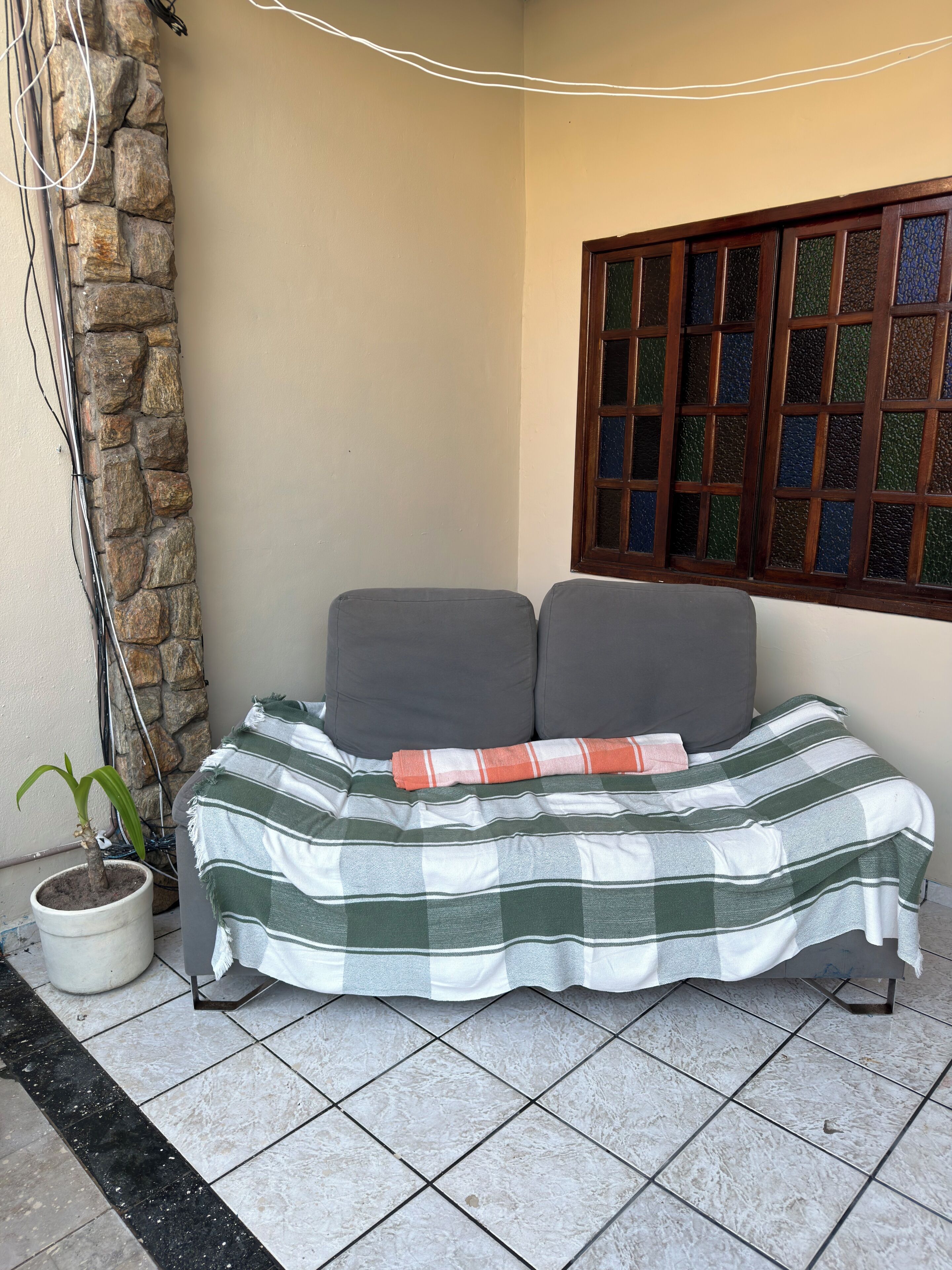 Uma cama com um cobertor listrado, uma planta em vaso e uma parede de pedra.