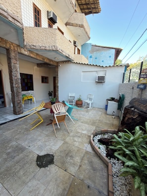 Un espacio al aire libre con piso de baldosas, mobiliario exterior y plantas en macetas.