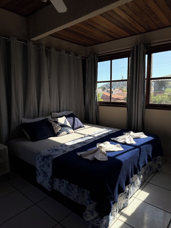 Un dormitorio con cama, cortinas, una ventana y vistas al exterior.