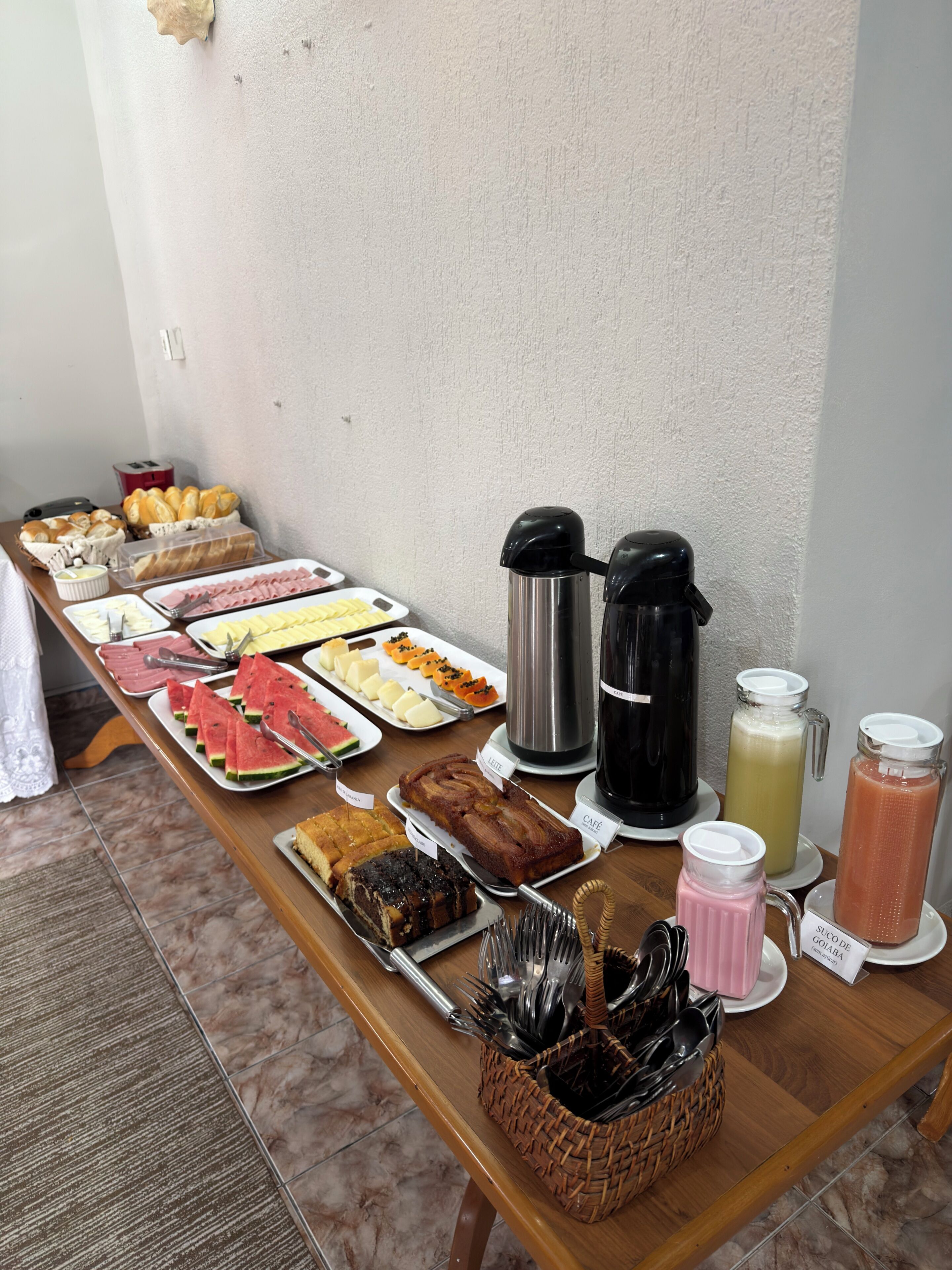 A buffet table with various food items, coffee makers, and a beverage dispenser.