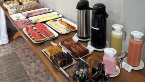 Una mesa de buffet con diferentes alimentos, cafeteras y un dispensador de bebidas.