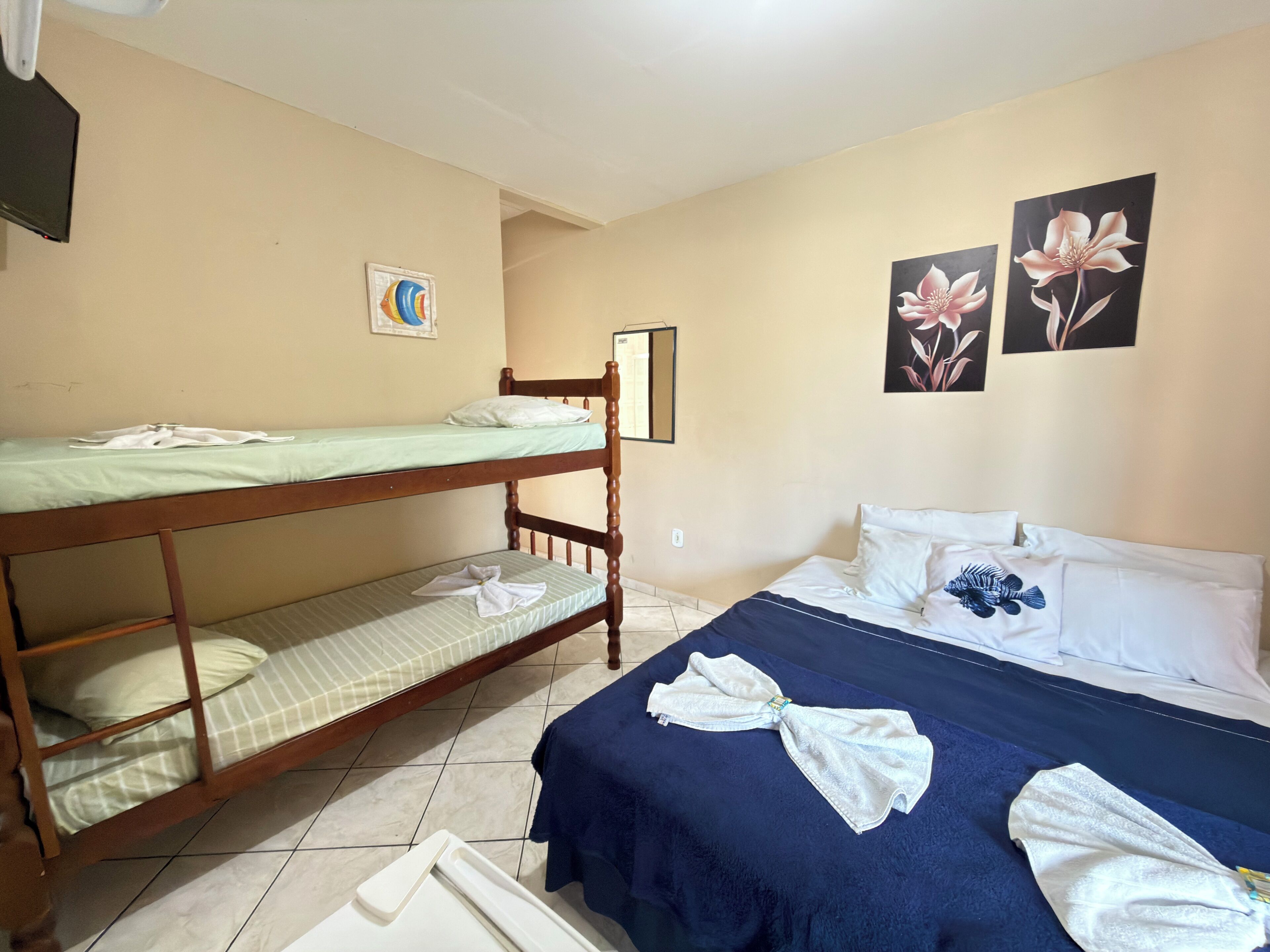 Ein Zimmer mit Etagenbetten, einem Einzelbett, einer blauen Decke und Handtüchern.