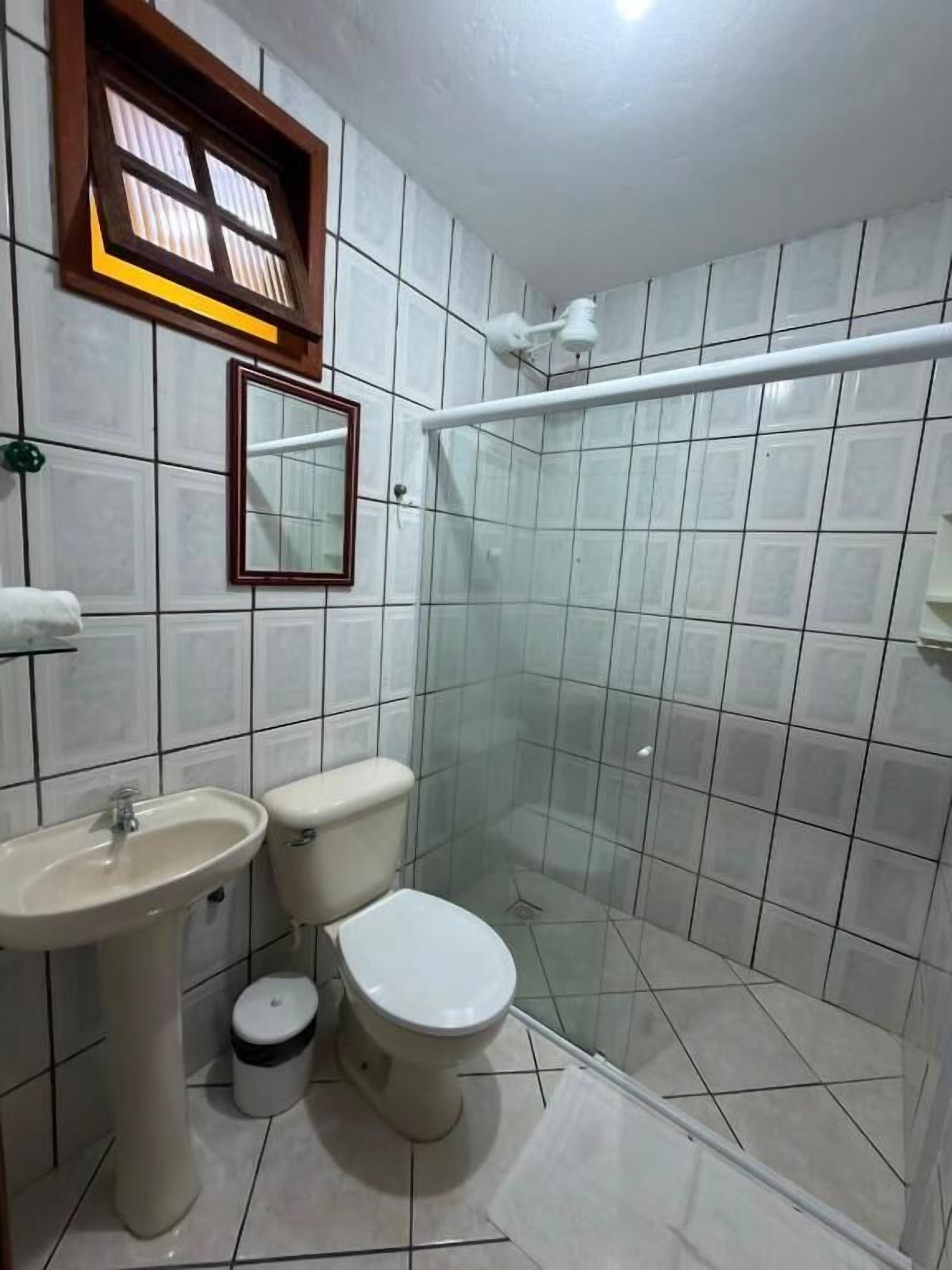 Casa de banho com sanita, lavatório e zona de duche.