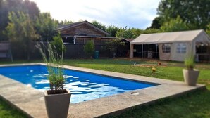 Una piscina amb zona verda i una casa al fons.