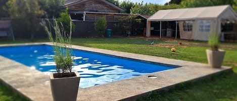 A swimming pool with a grassy area and a house in the background.