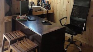 A wooden-paneled room with a desk, computer, and office chair. - Ocean Reach Holidays (Mirissa)