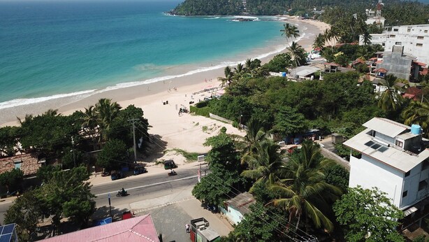 A coastal area with a beach, buildings, and a road. - Ocean Reach Holidays (Mirissa)