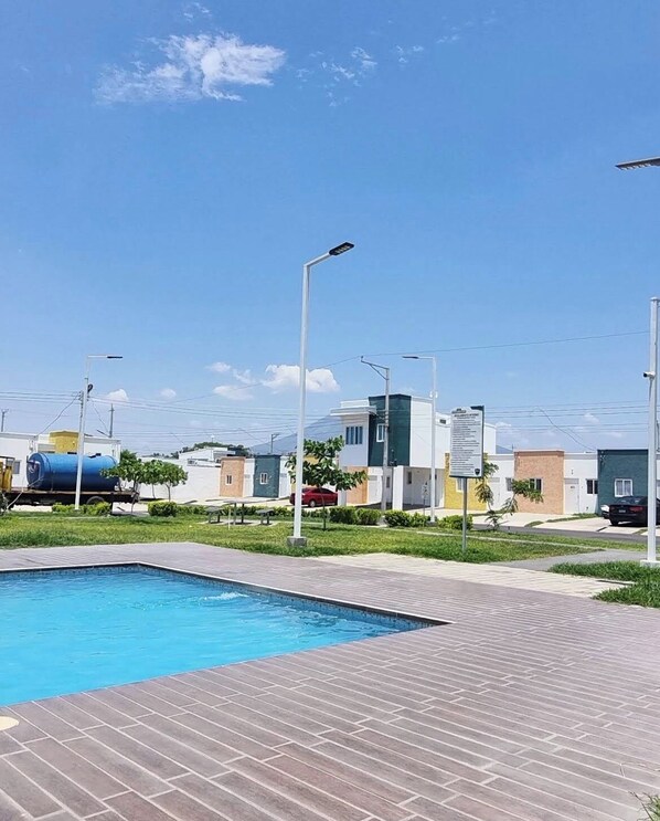 Una piscina con plataforma pavimentada, rodeada de edificios modernos y farolas.