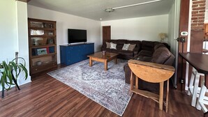 A living room with a brown leather sofa, a wooden coffee table, a blue cabinet, and a television.