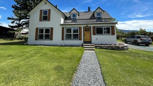 A two-story house with a gravel driveway and a wooden front door.