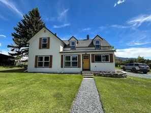 A two-story house with a gravel driveway and a wooden front door.