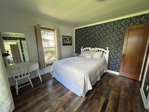 A bedroom with a bed, a desk, and a window.