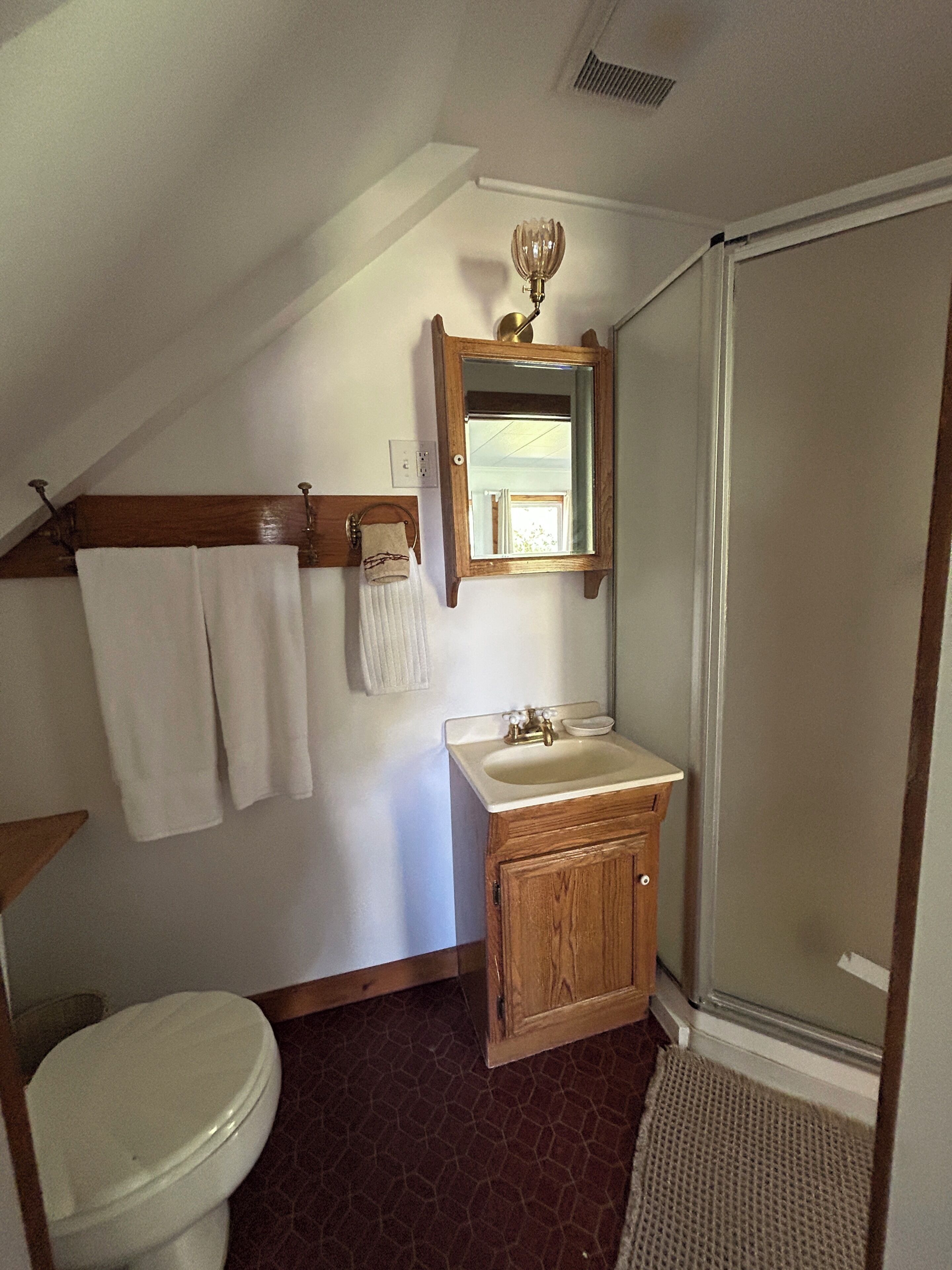 A bathroom with a toilet, sink, mirror, and shower.