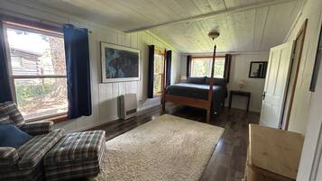 A bedroom with a bed, a window, a painting, and a heater.