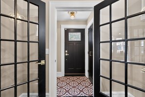 A hallway with black-framed glass doors, a patterned tile floor, and a black door with a window. - Historic Forest Hill Single Family Near NYC (Newark)