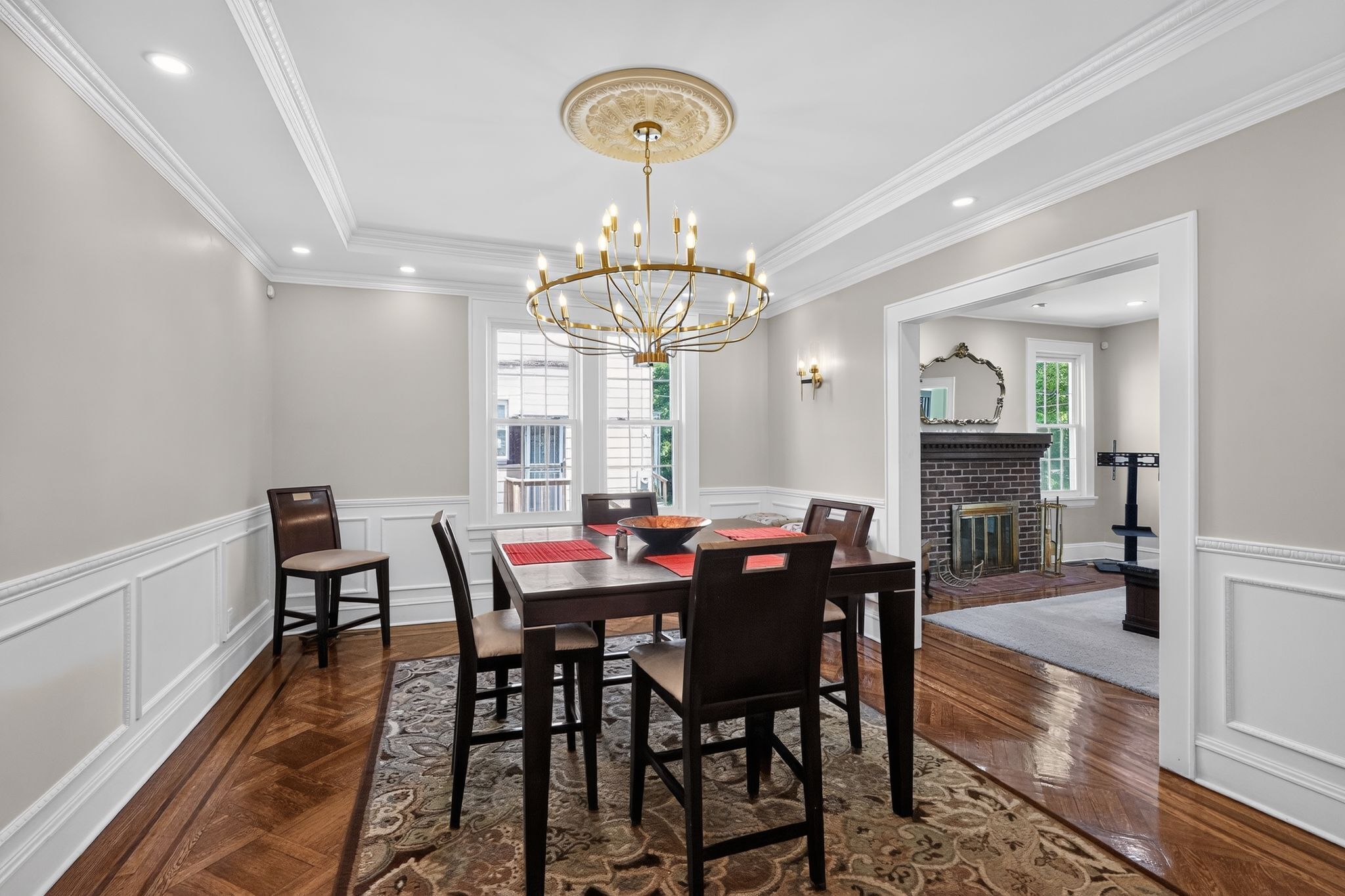A dining room with a chandelier, wooden table, chairs, and a rug.