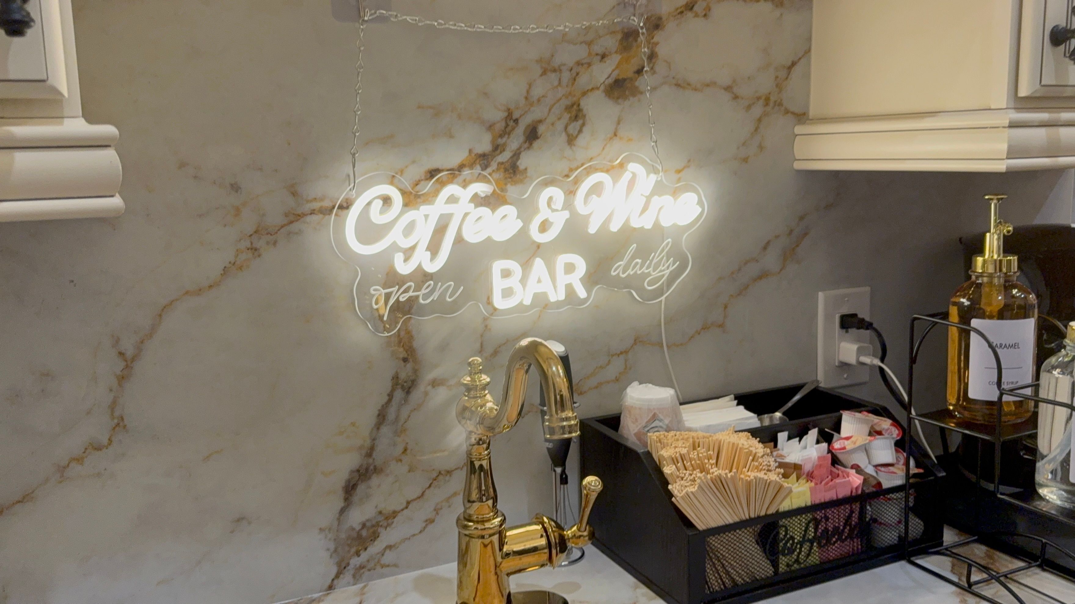 Un mur de marbre orné d’un néon indiquant « Café et bar à vin, ouvert tous les jours » et d’un robinet doré.