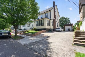 A residential street with houses, a driveway, and a tree. - Historic Forest Hill Single Family Near NYC (Newark)