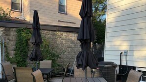 Eine Terrasse im Freien mit Tisch und Stühlen, umgeben von einer Steinmauer und einem Haus.