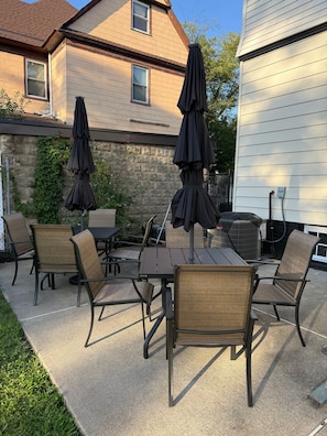 An outdoor patio with a table and chairs, surrounded by a stone wall and a house. - Historic Forest Hill Single Family Near NYC (Newark)