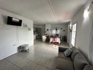 A living room with a sofa, a television mounted on the wall, and a dining area with a table and chairs. - Horizonte Profundo Rustic Retreat Near Combate Beach, sleeps 8 (Combate)
