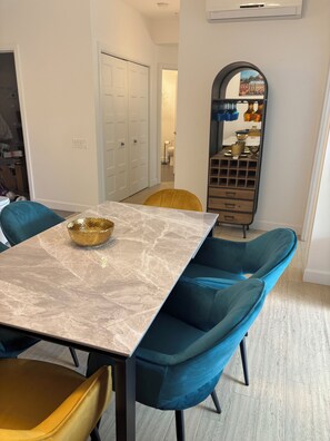 A dining area with a marble table, teal upholstered chairs, and a golden bowl. - Le Diamant Bleu in Quebec City ~GYM~GARAGE~Downtown (Québec)