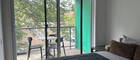 Ein Schlafzimmer mit großem Fenster, einem Bett und Blickrichtung nach draußen.