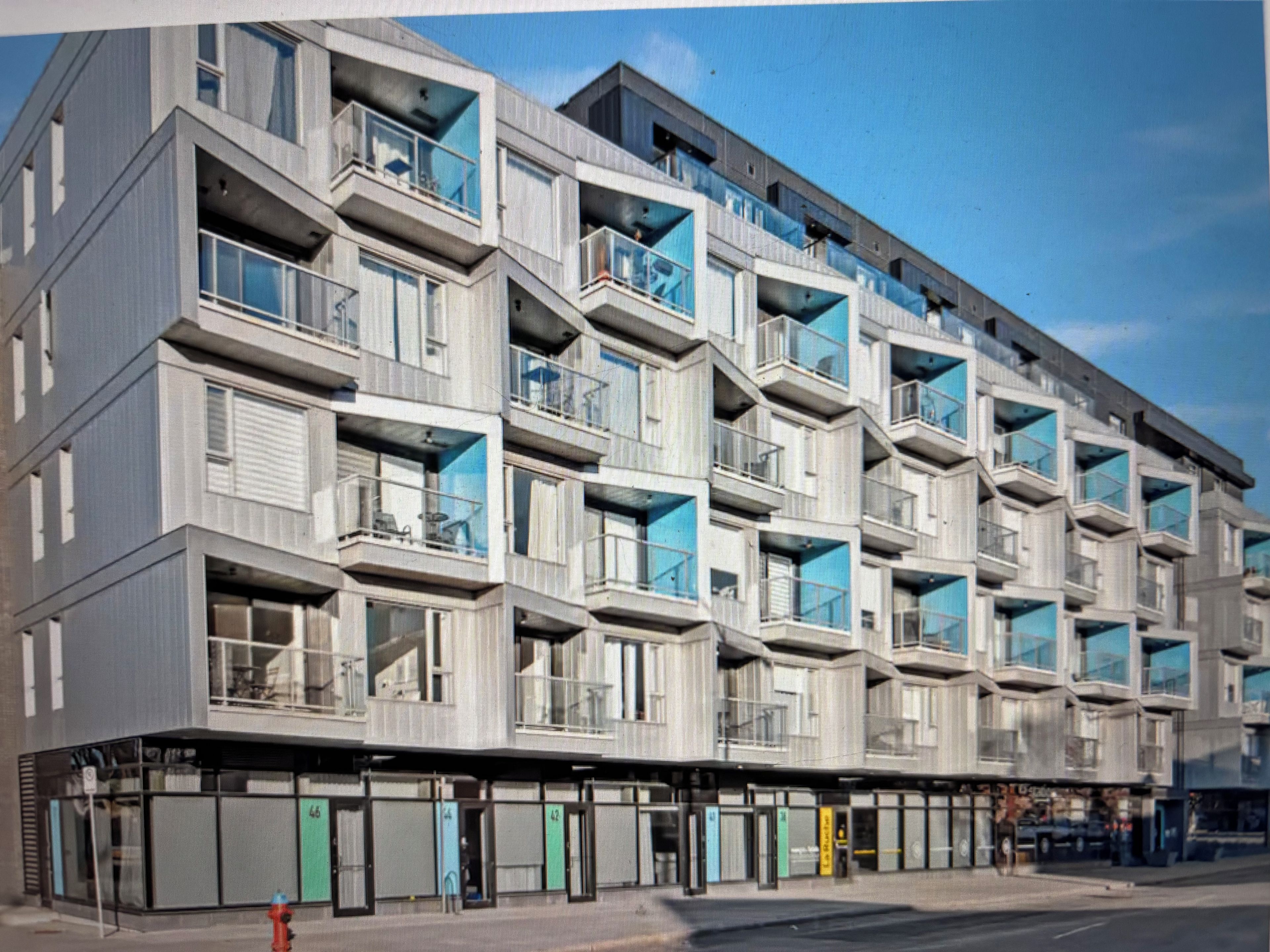 A multi-story building with balconies and a ground-level commercial area.