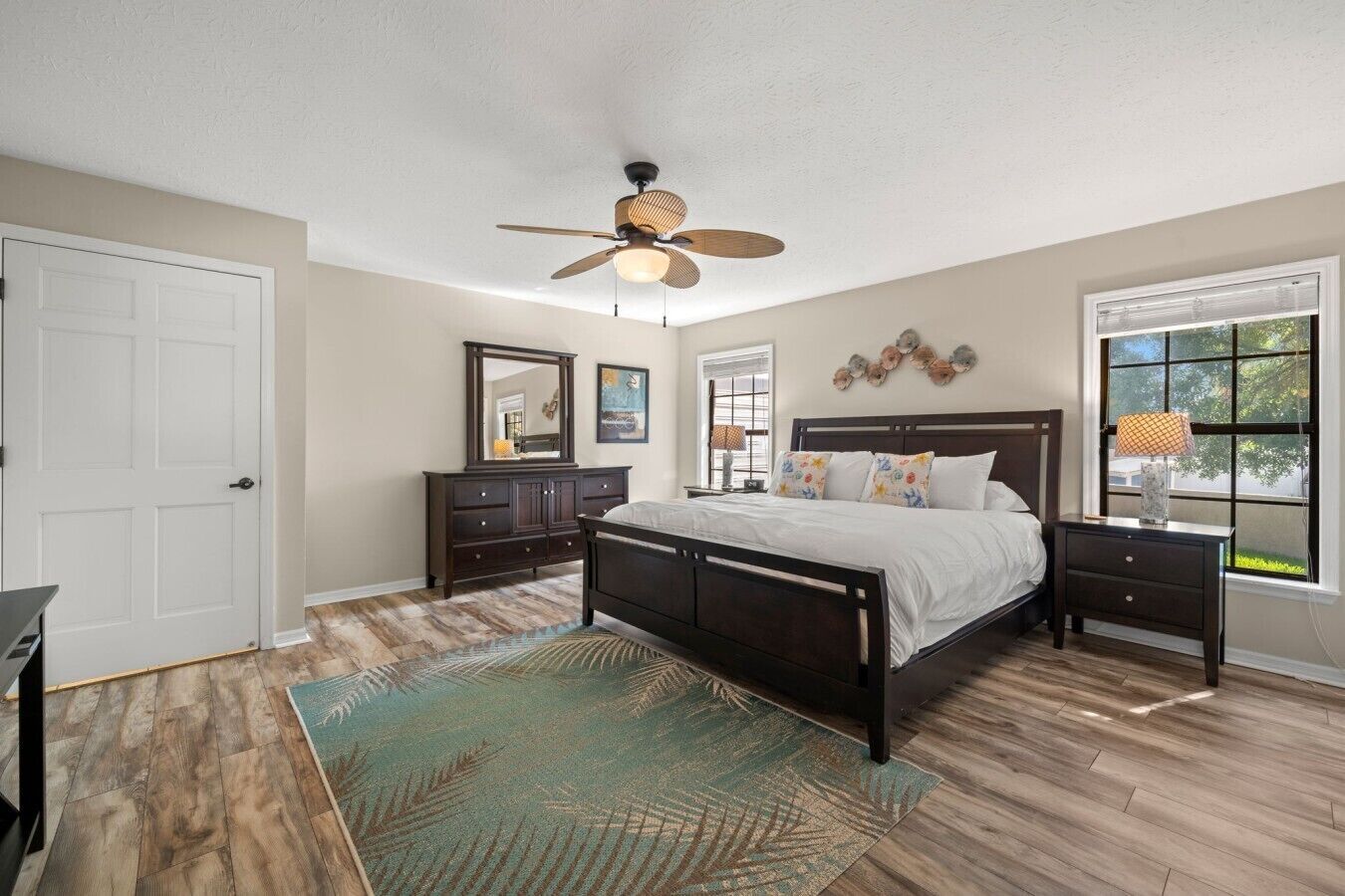 A bedroom with a bed, a dresser, a ceiling fan, a window with blinds, and a rug.