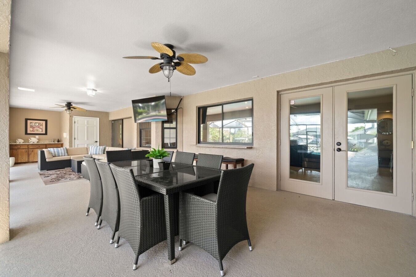 A dining area with a table and chairs, a ceiling fan, and a television mounted on the wall.