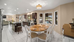 A spacious kitchen with a dining area, white chairs, and a central island. - Peaceful, Canal Front Home w/ Heated Pool - Surfside Beach House (Apollo Beach)