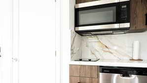 Uma cozinha com micro-ondas, máquina de lavar louça e bancada de mármore.