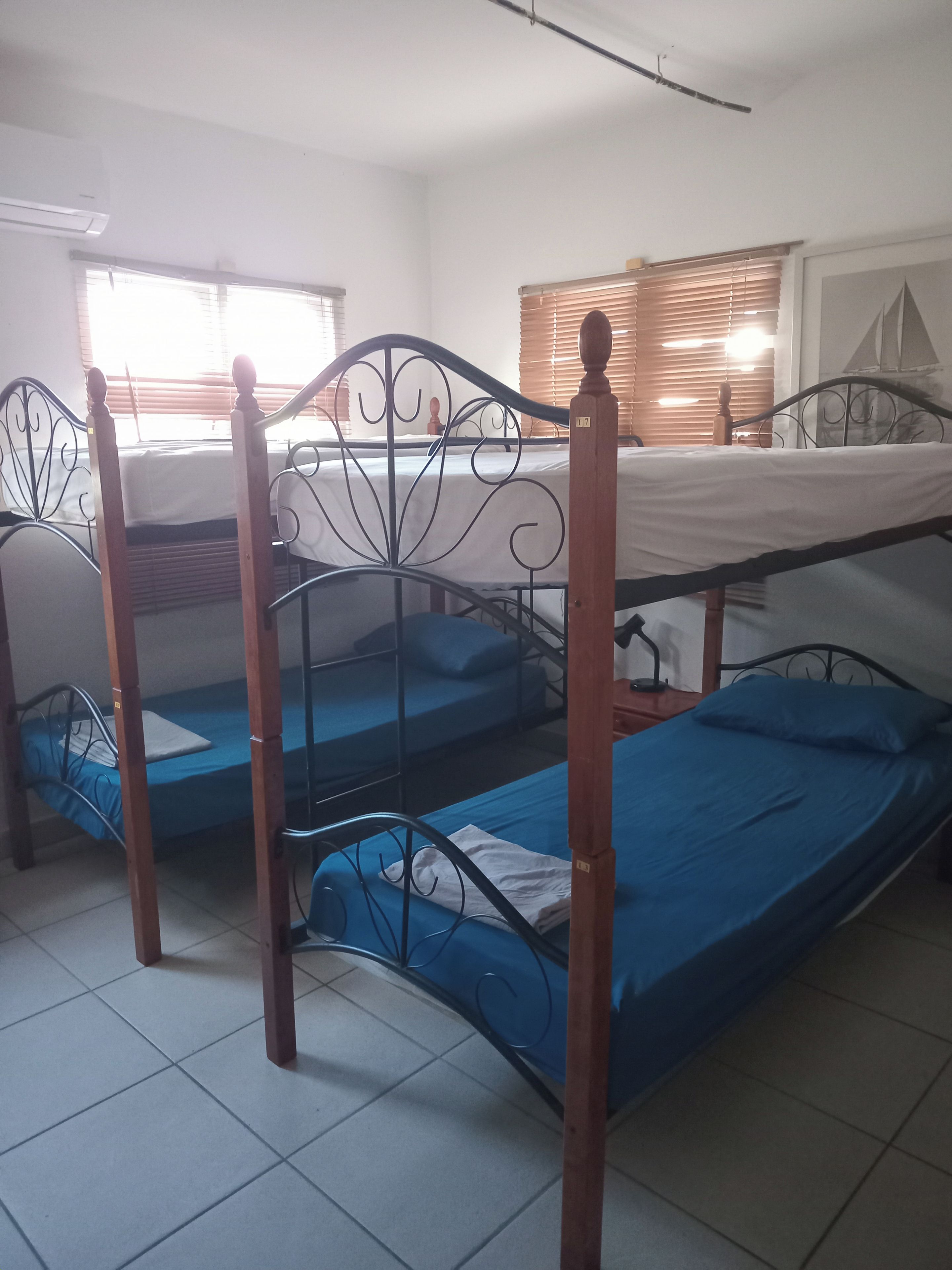 Un dormitorio con literas, una ventana con persianas y un equipo de aire acondicionado.