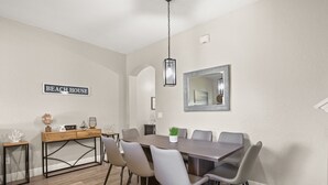 A dining area with a long table, six chairs, a wooden side table, a globe, and a sign reading 'BEACH HOUSE'. - 4 BD/ 3 BA/ Regal Palms (3214 CA) (Davenport)