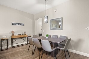 Un comedor con una mesa larga, seis sillas, una mesita de madera, un globo terráqueo y un cartel que dice 'BEACH HOUSE'.