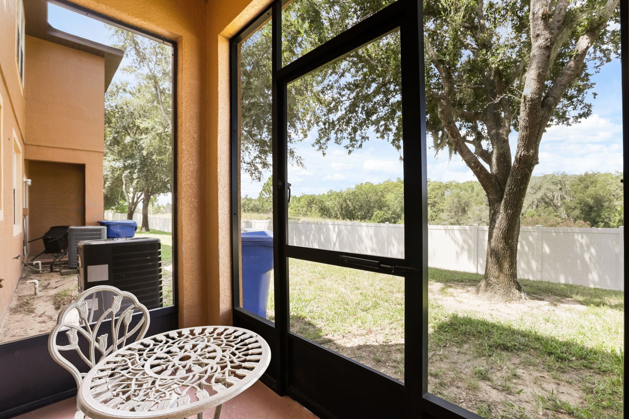 Una habitación con vista a un patio cercado, una mesa y una silla.