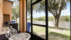 A room with a view of a fenced yard, a table, and a chair. - 4 BD/ 3 BA/ Regal Palms (3214 CA) (Davenport)