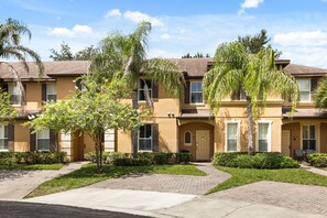 A row of townhouses with a paved walkway, green lawns, and palm trees. - 4 BD/ 3 BA/ Regal Palms (3214 CA) (Davenport)