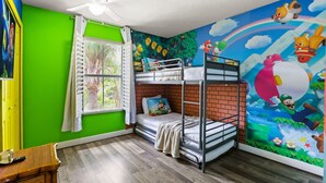 A room with a bunk bed, a window with curtains, a ceiling fan, and a mural with animated characters. - 4 BD/ 3 BA/ Regal Palms (3214 CA) (Davenport)