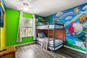A room with a bunk bed, a window with curtains, a ceiling fan, and a mural with animated characters. - 4 BD/ 3 BA/ Regal Palms (3214 CA) (Davenport)