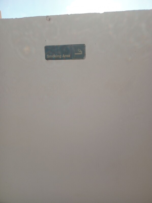 A wall with a sign indicating a smoking area.