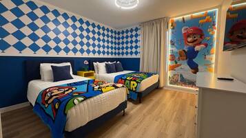 Une chambre avec deux lits, un ventilateur de plafond et une fresque murale sur le thème de Mario.