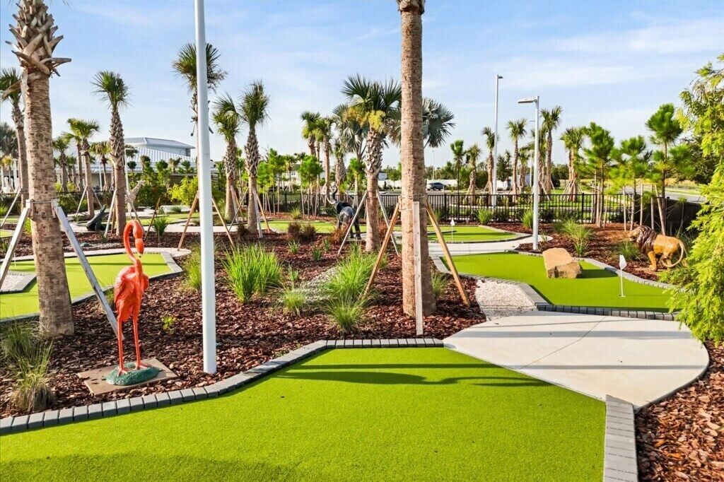 A well-maintained golf course with manicured grass, palm trees, and a sculpture of a flamingo.